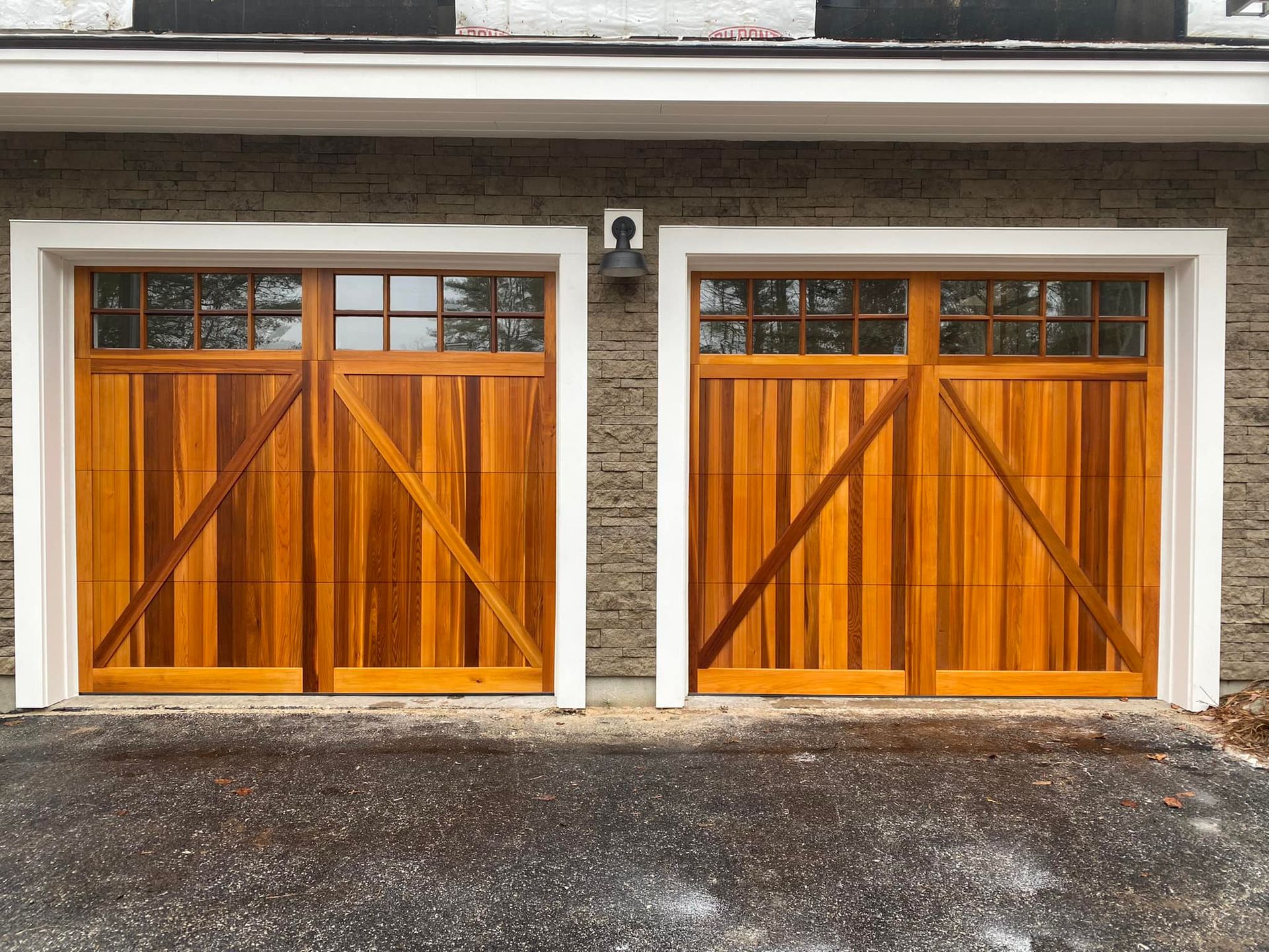 A pair of wooden garage doors on a brick building.
