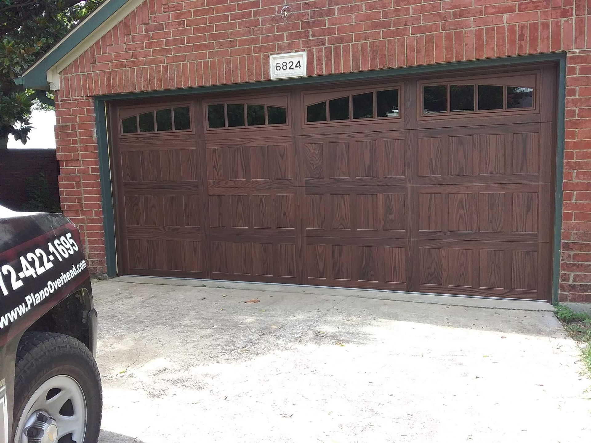 A truck is parked in front of a brick garage door.