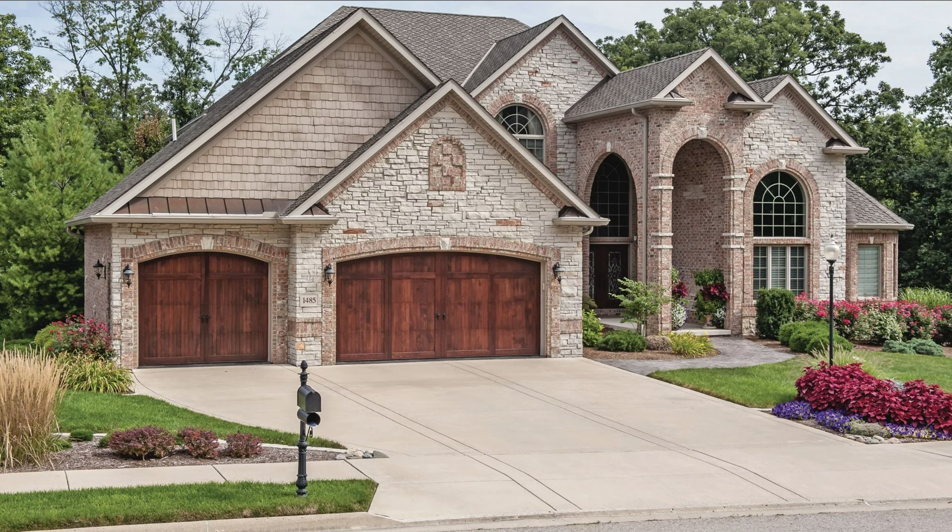 A large brick house with two wooden garage doors
