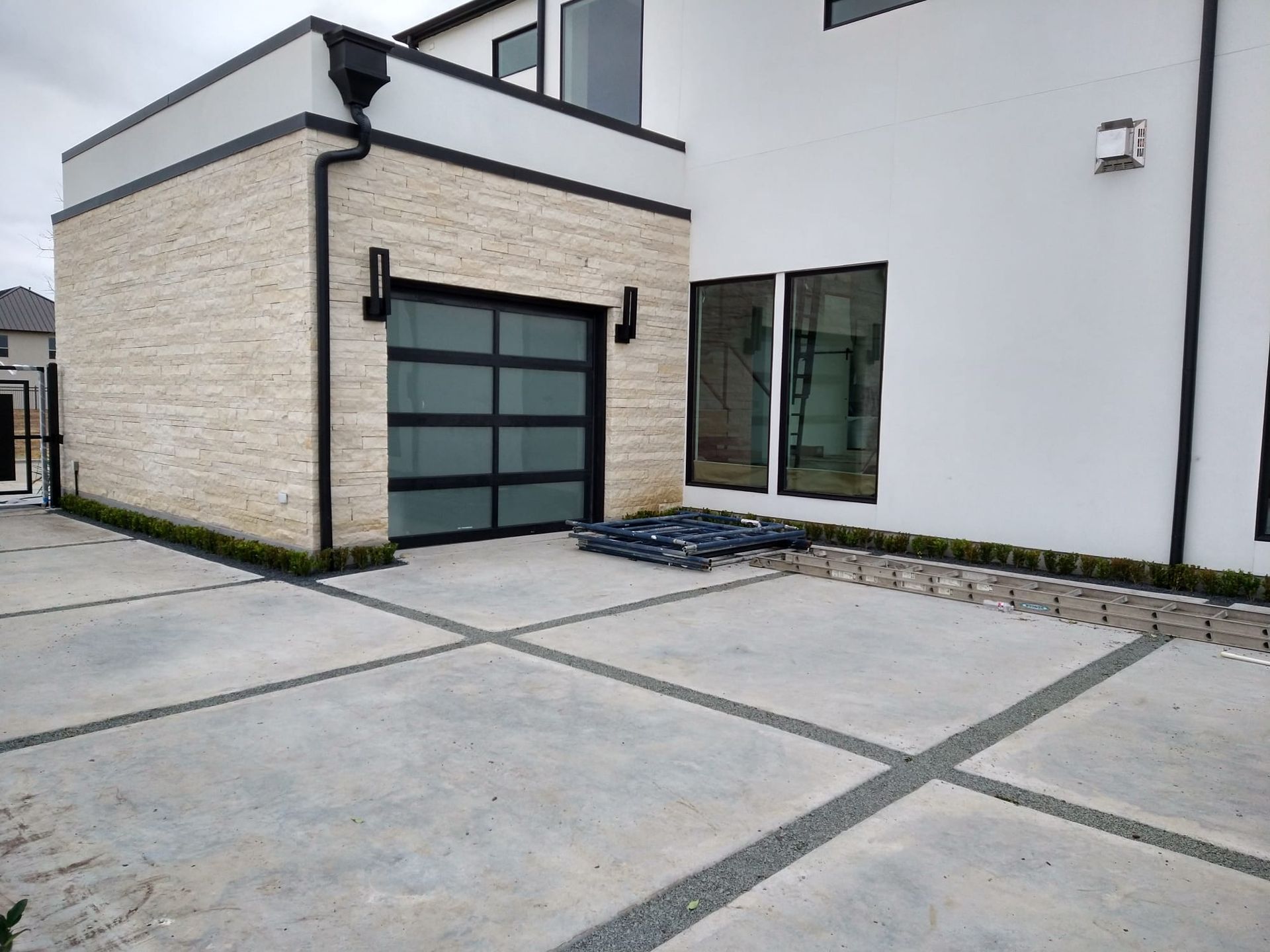 A white house with a black garage door and a concrete driveway