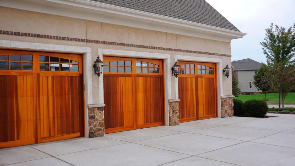 A house with three wooden garage doors and a concrete driveway.