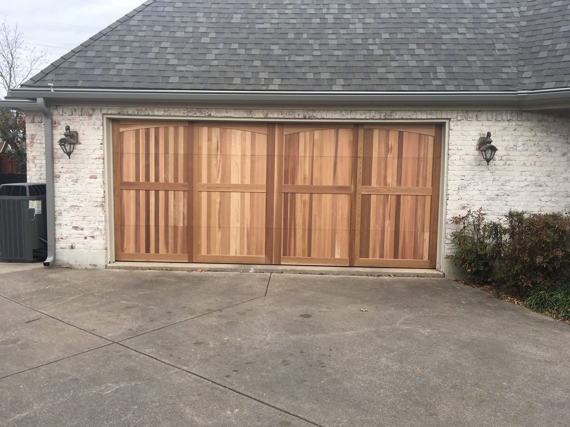 A white brick house with a wooden garage door