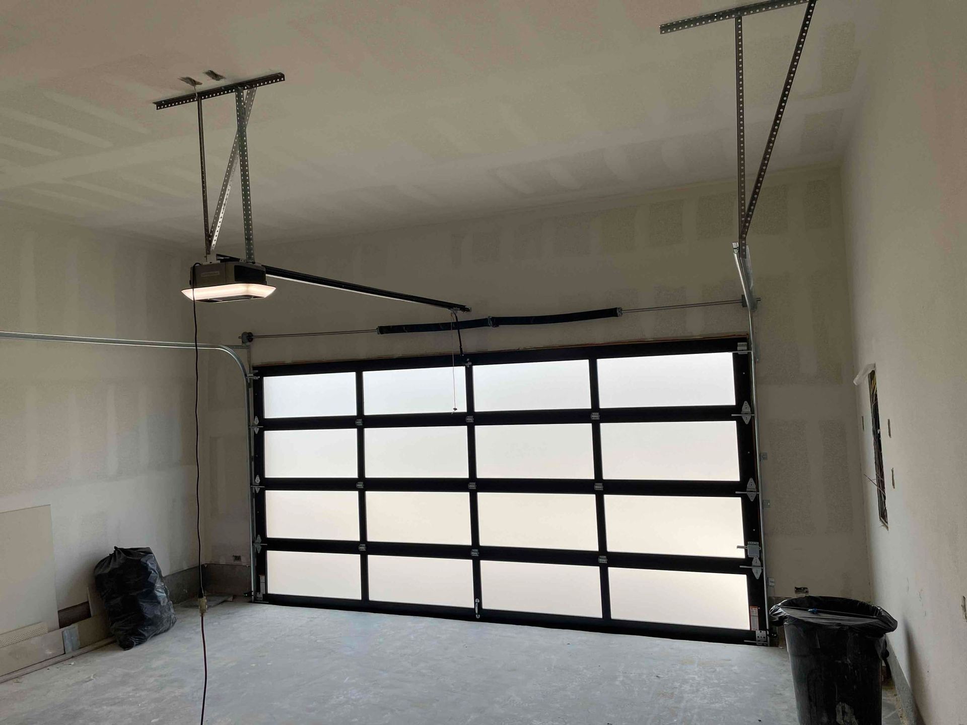 A garage with a garage door open and a light hanging from the ceiling.