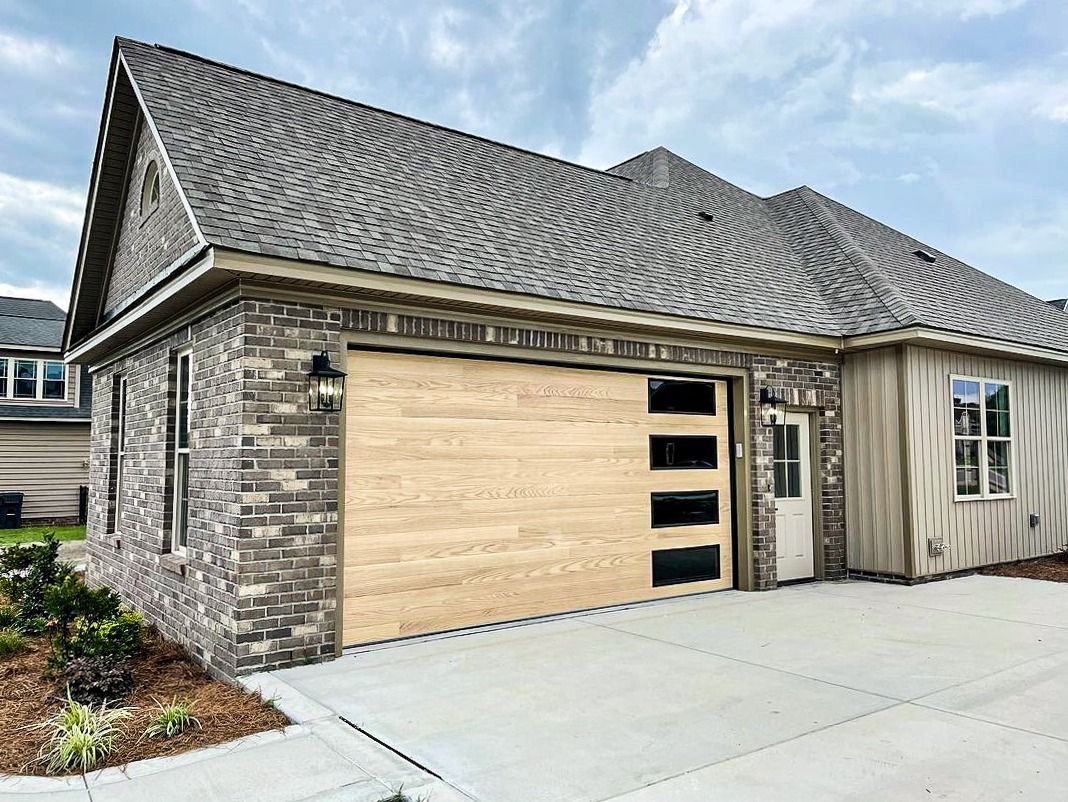 A house with a wooden garage door and a concrete driveway.