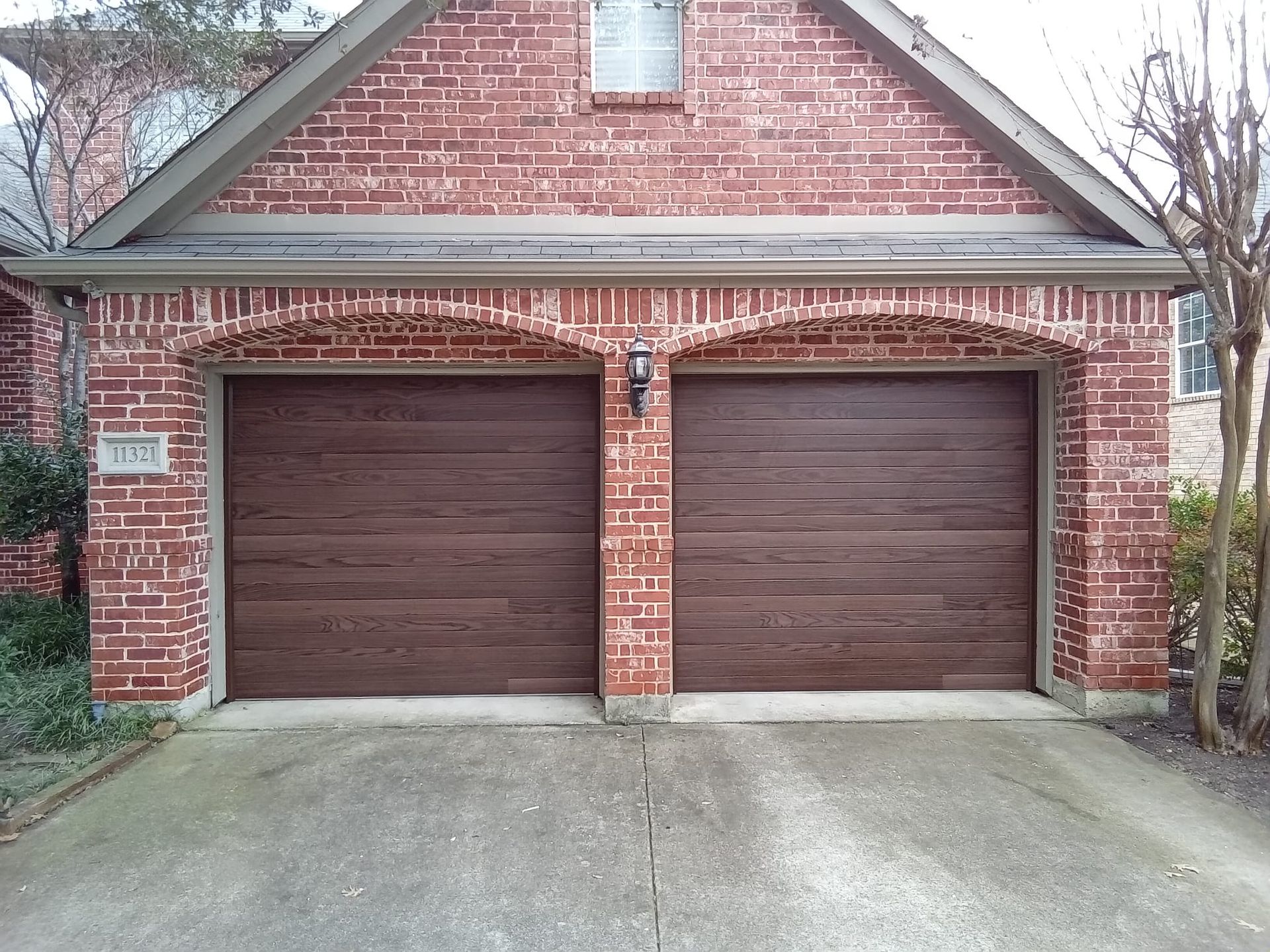 A red brick house with two brown garage doors