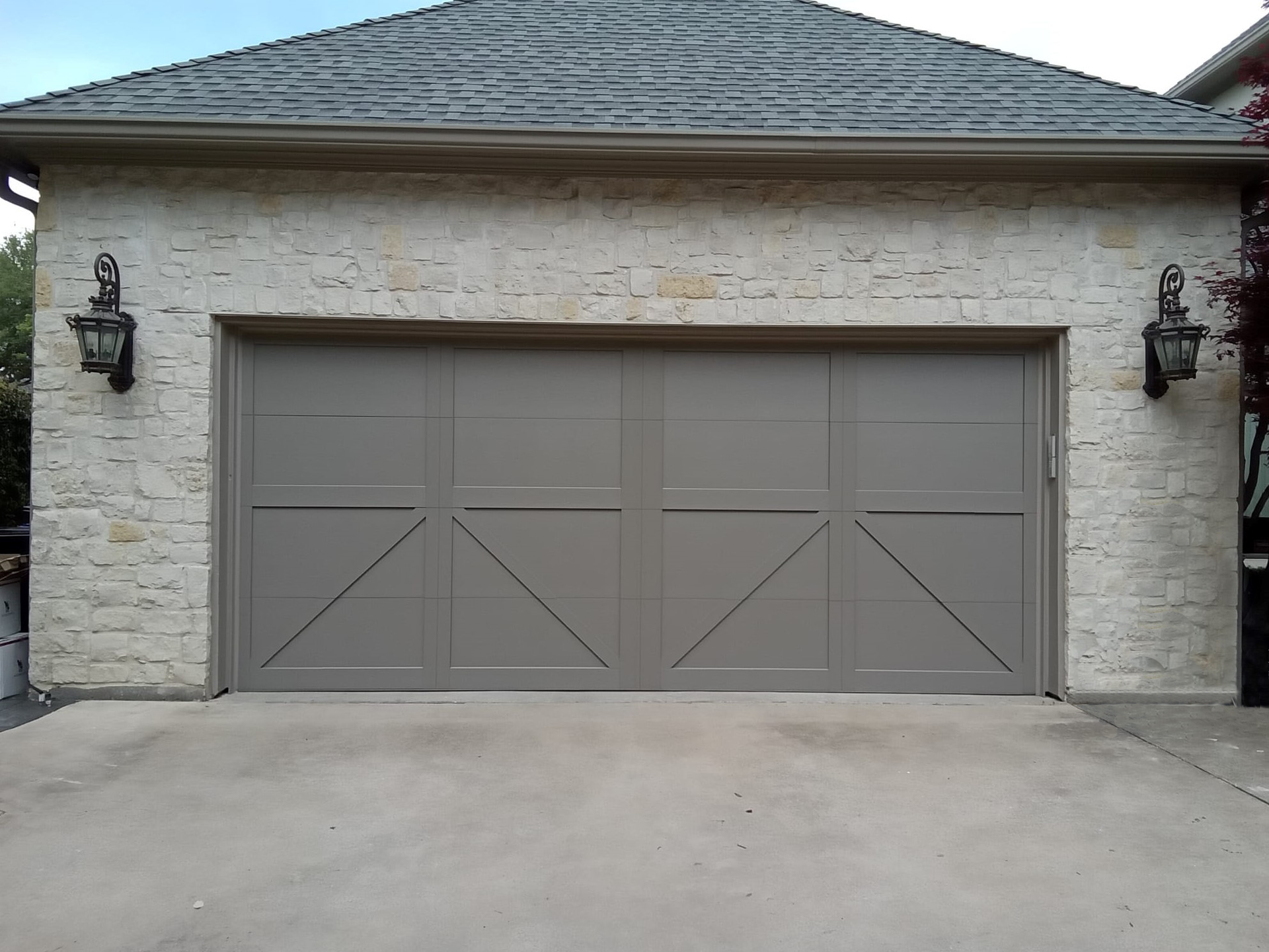 A gray garage door with a brick building in the background