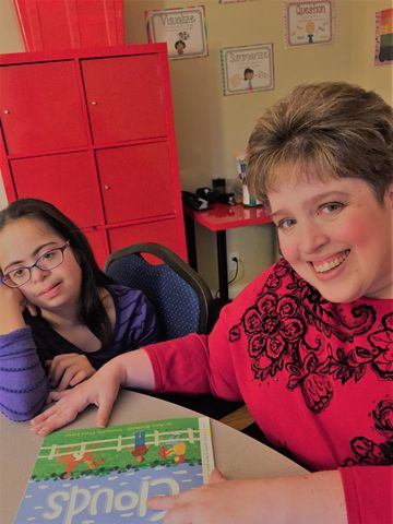 a woman in a red sweater is helping a boy with a piece of paper