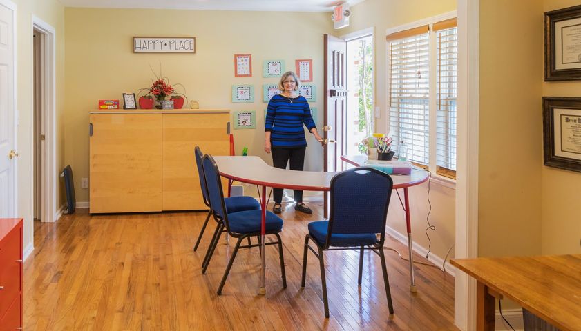 a woman in a red sweater is helping a boy with a piece of paper