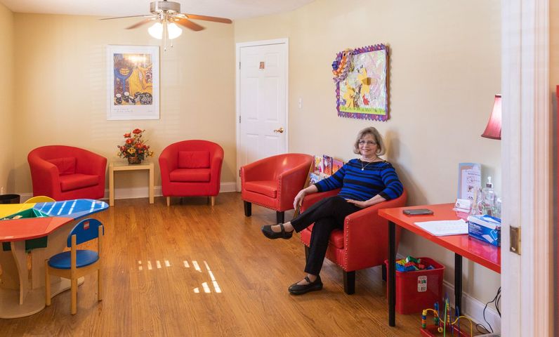a woman in a red sweater is helping a boy with a piece of paper
