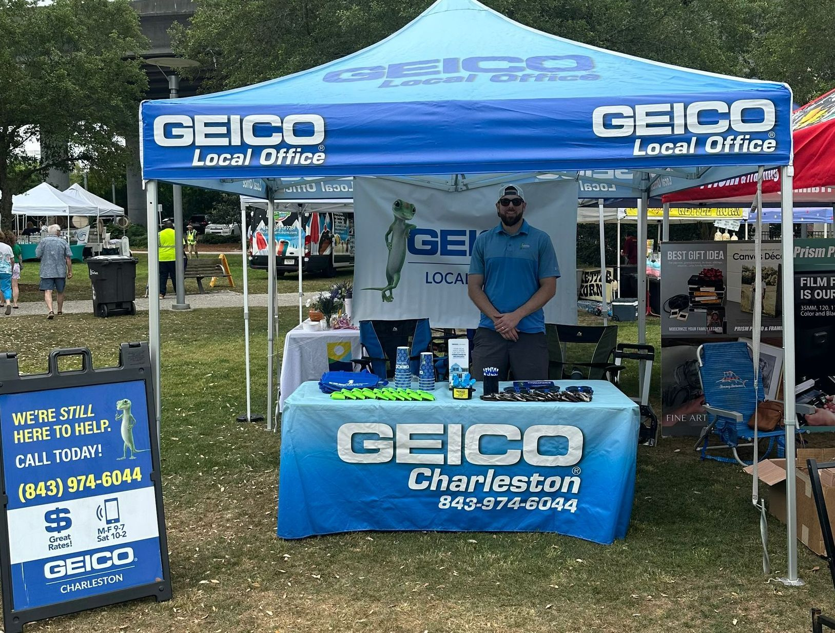 A man stands at a GEICO Local Office tent in Charleston. 