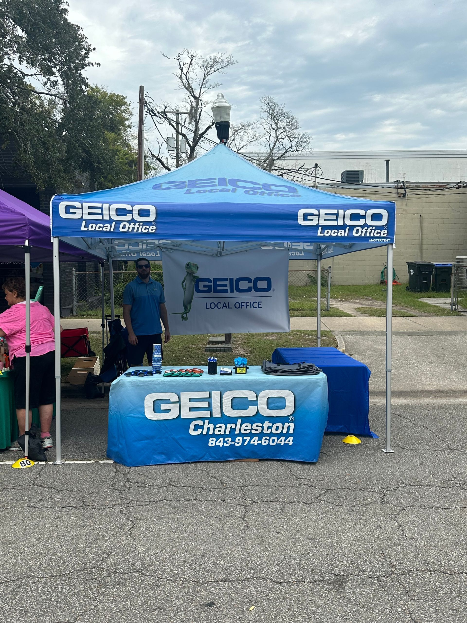 GEICO Local Office tent in Charleston with a person standing behind the table with the company’s logo.