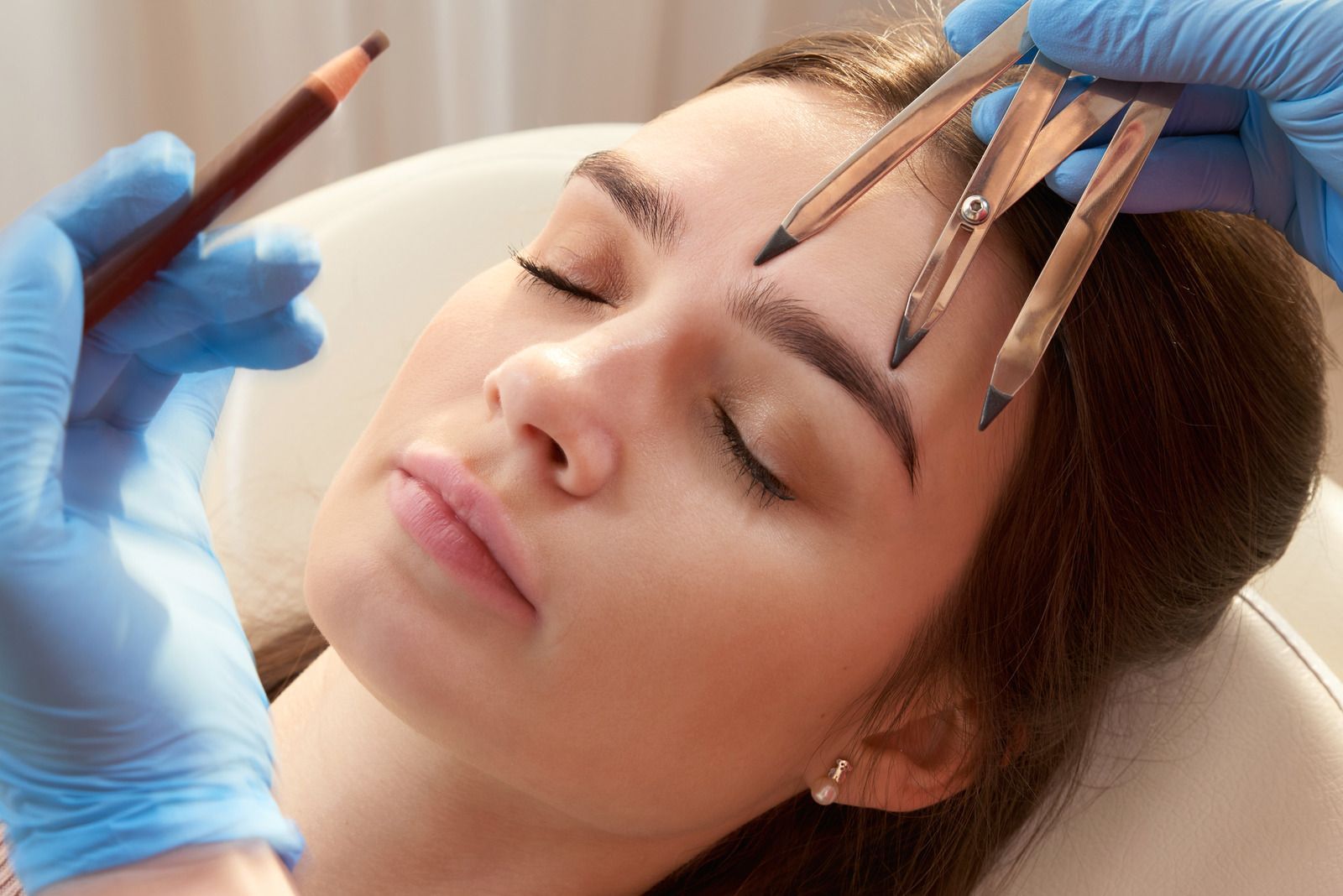 A woman is getting her eyebrows drawn by a makeup artist.
