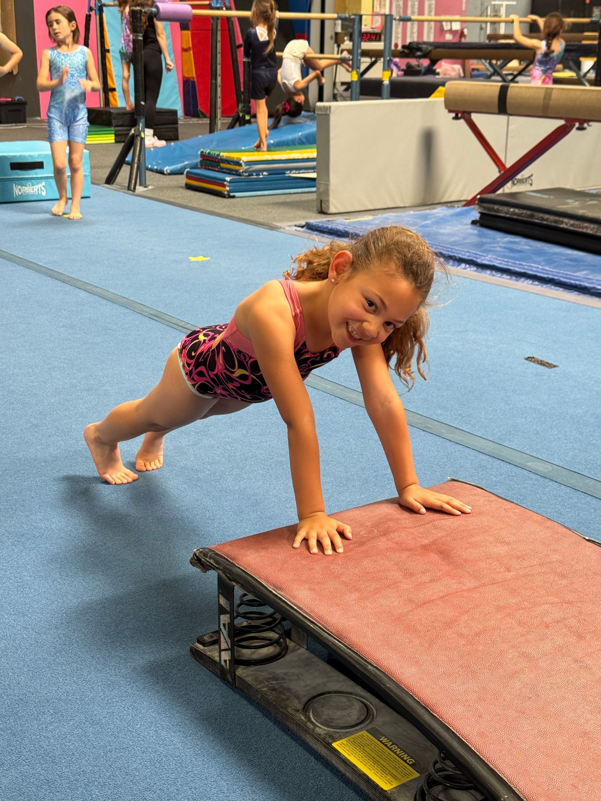 A gymnast is sitting on a balance beam covered in chalk.