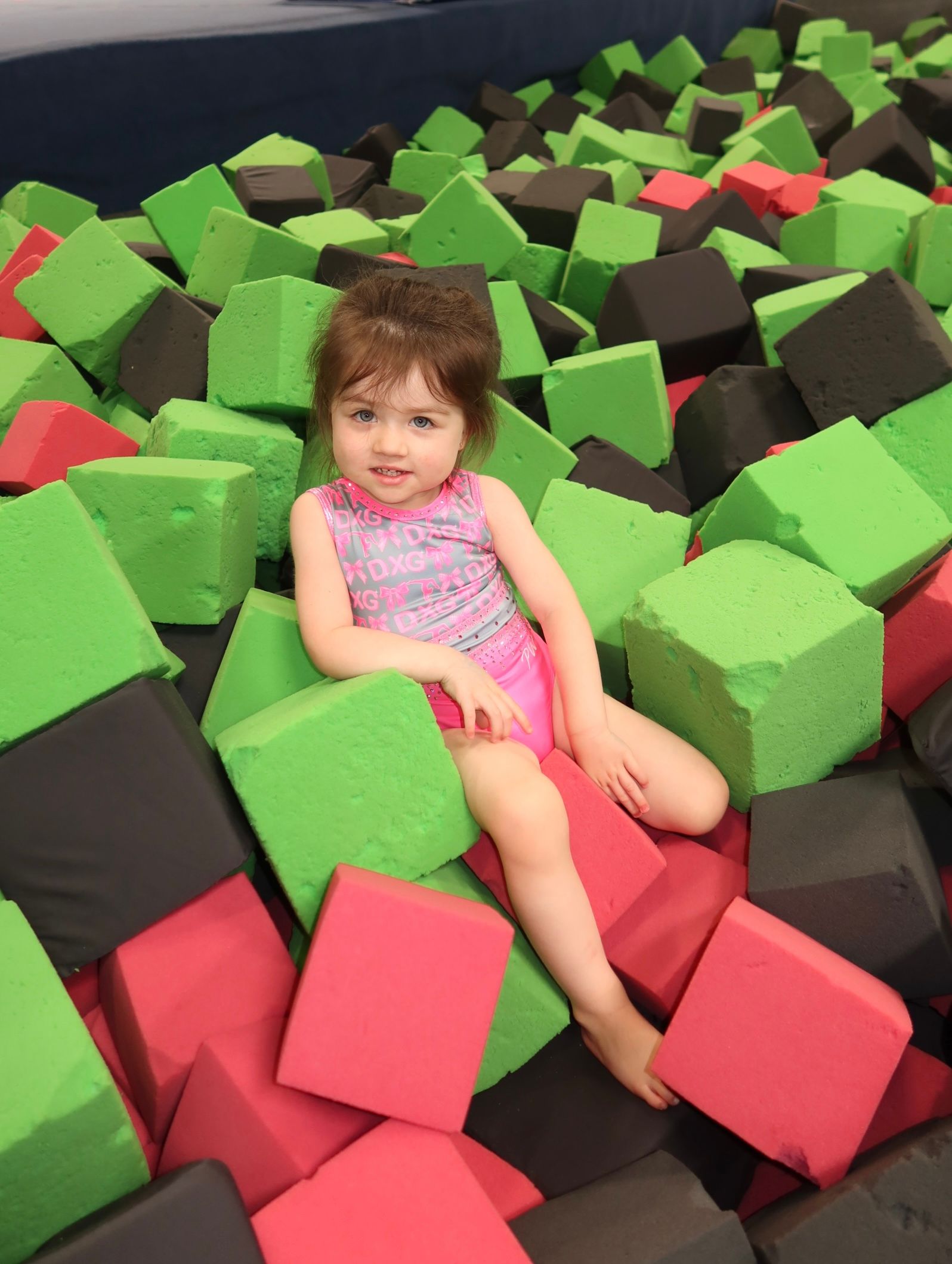 A young girl is doing a split on the floor in a gym.