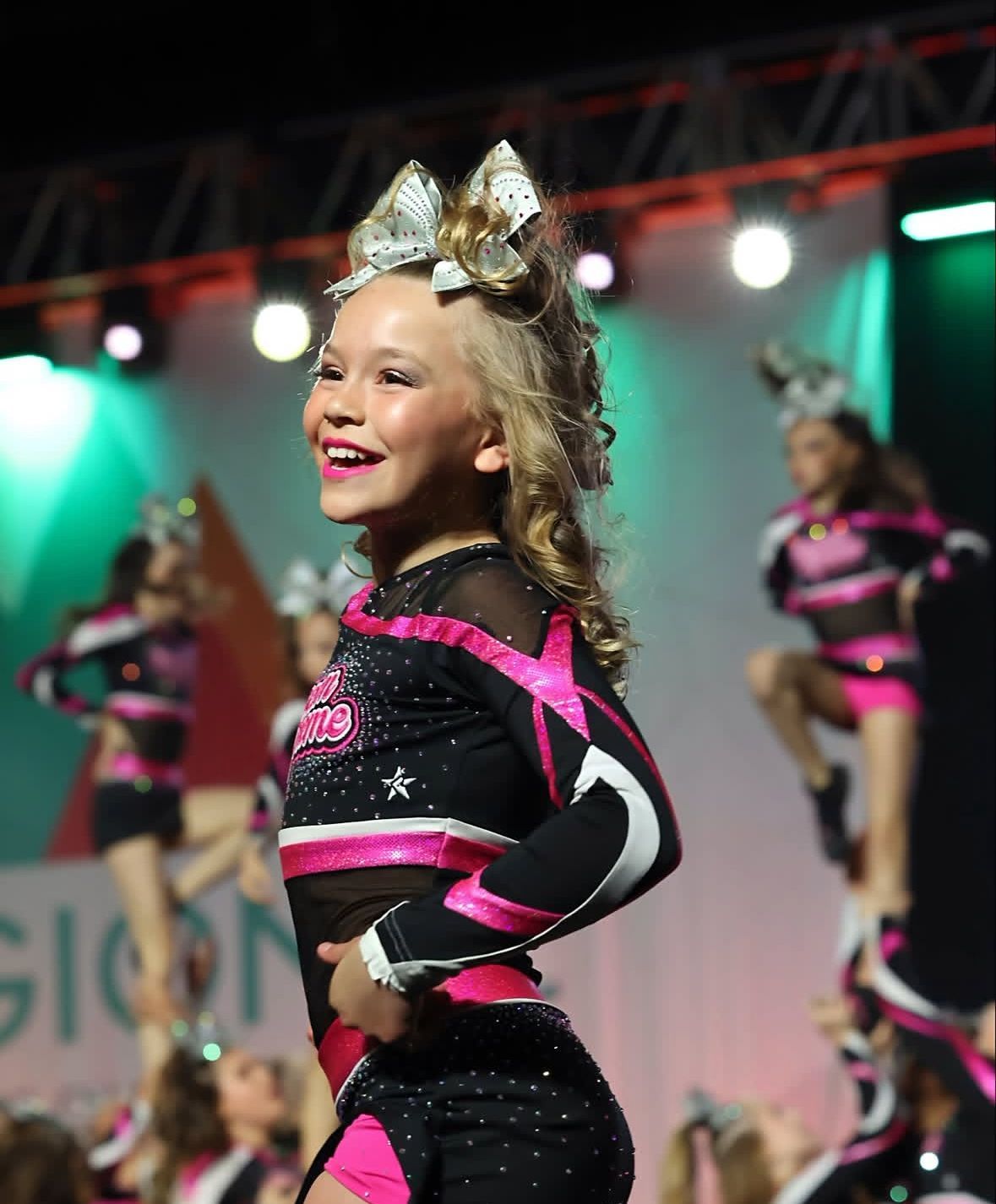 A little girl in a cheerleading outfit is smiling