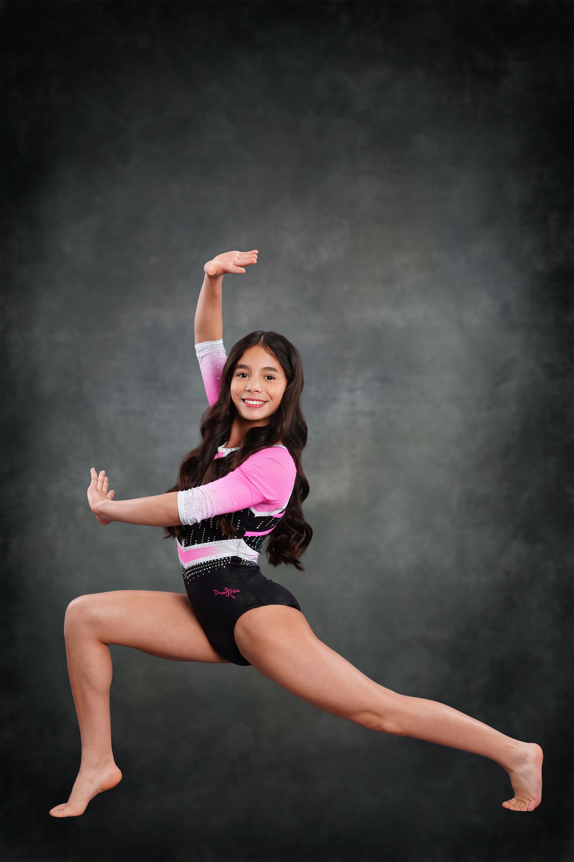 A woman in a black leotard is standing on one leg.