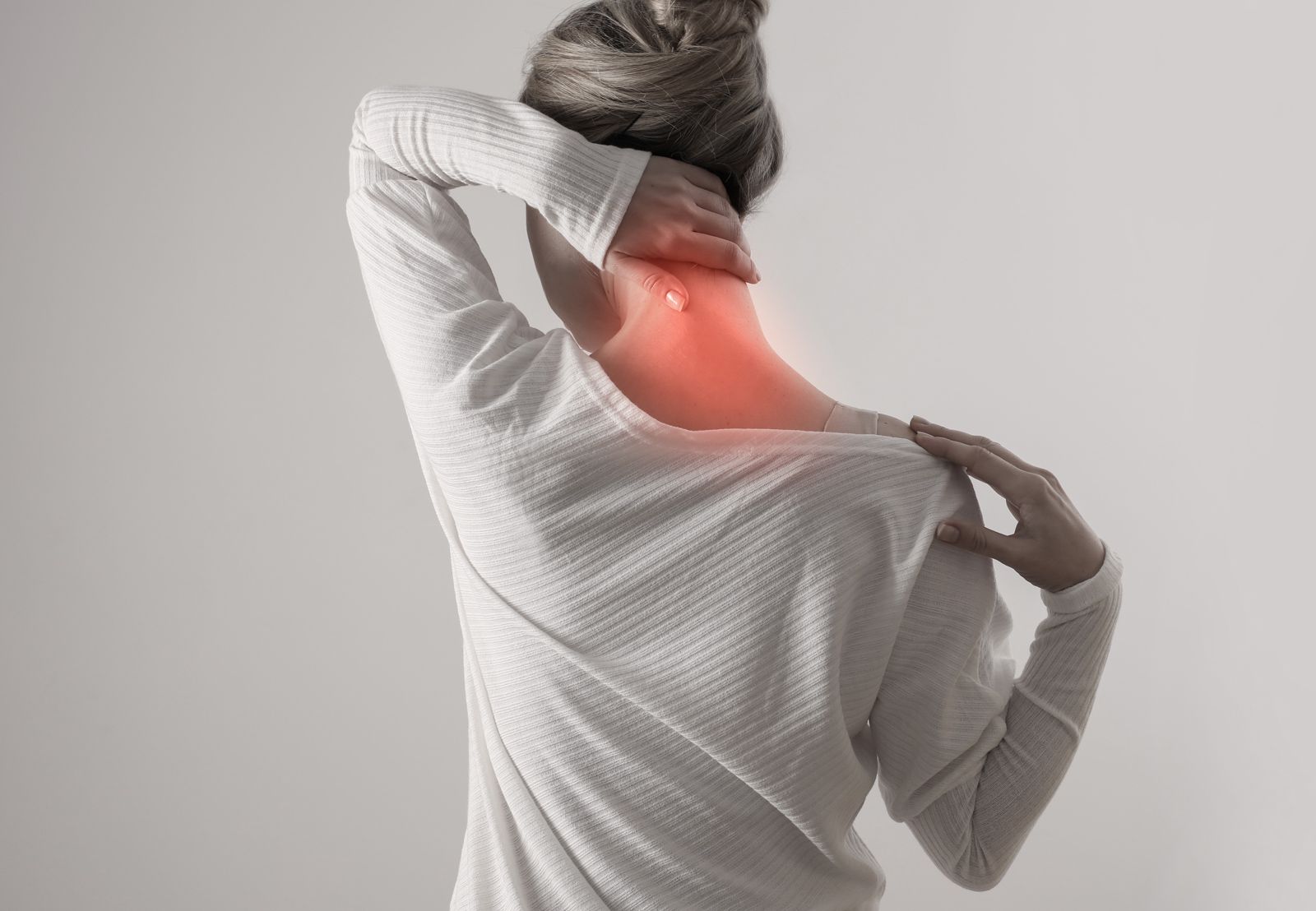 A woman is holding her neck in pain