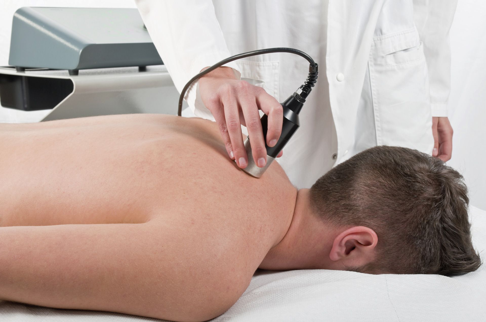 A man is laying on a bed getting a laser therapy