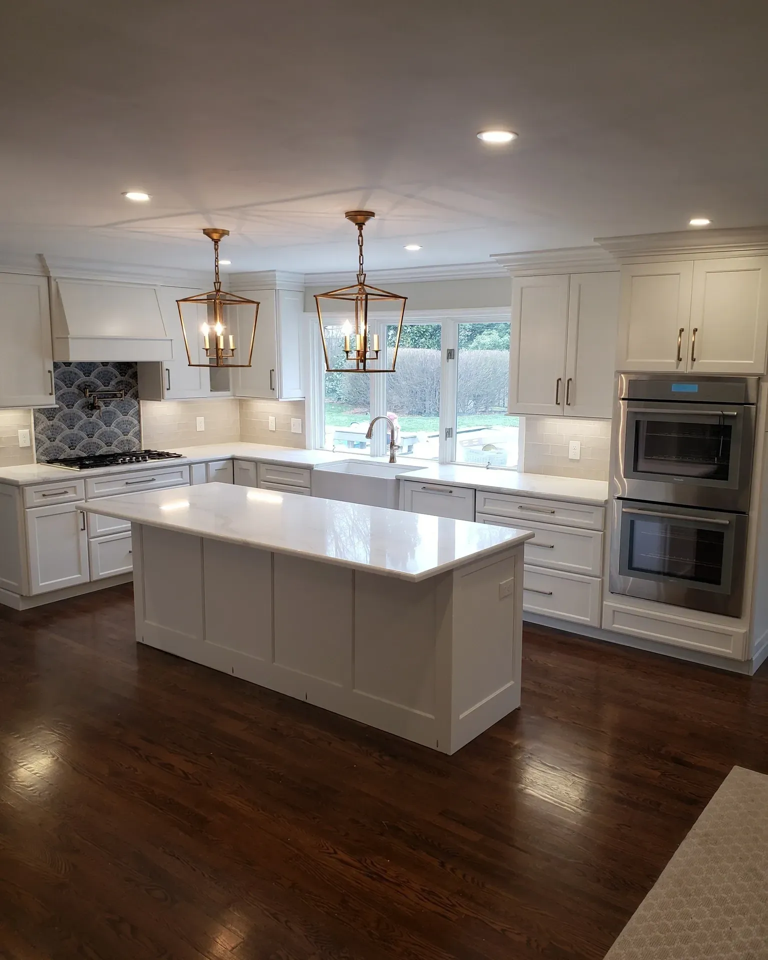 Modern kitchen with white cabinets, island, quartz countertops, and dark hardwood floors.