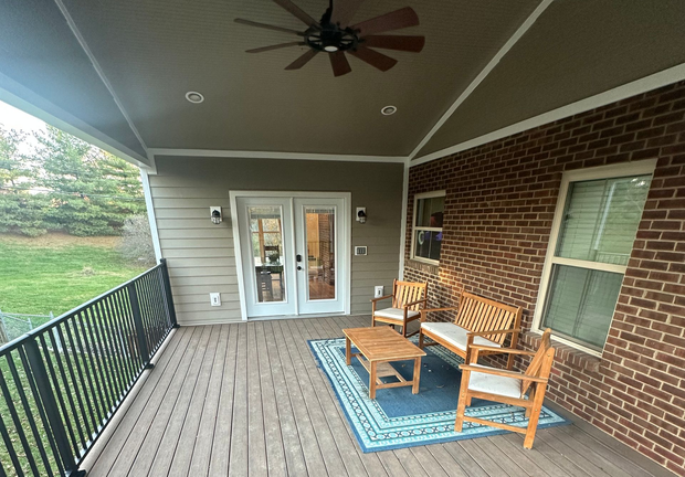 Covered deck with outdoor furniture, brick wall, and a view of the yard.