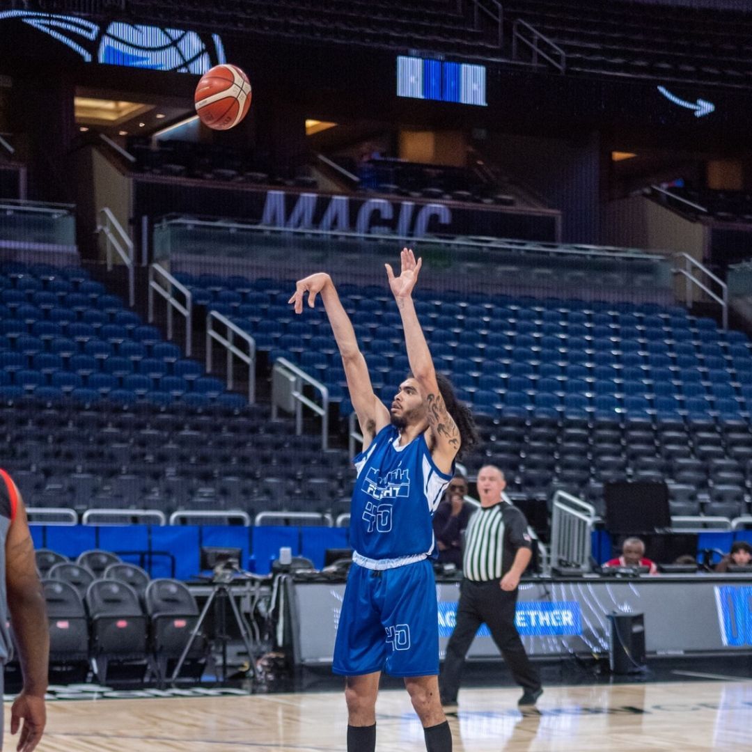 A basketball player throws a ball in front of a sign that says magic