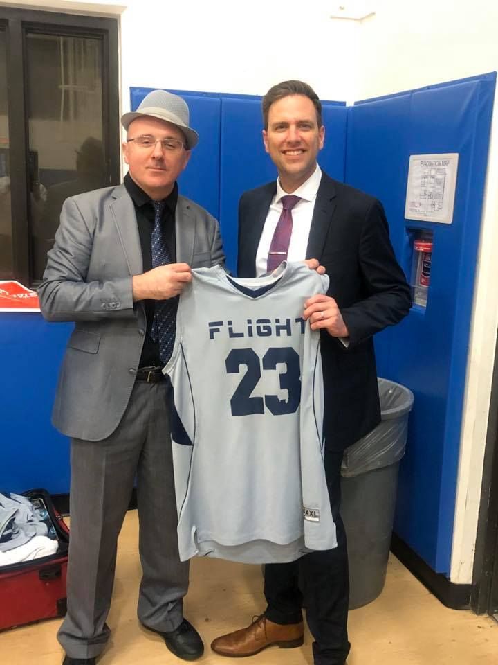 A man in a suit is holding a jersey with the number 23 on it