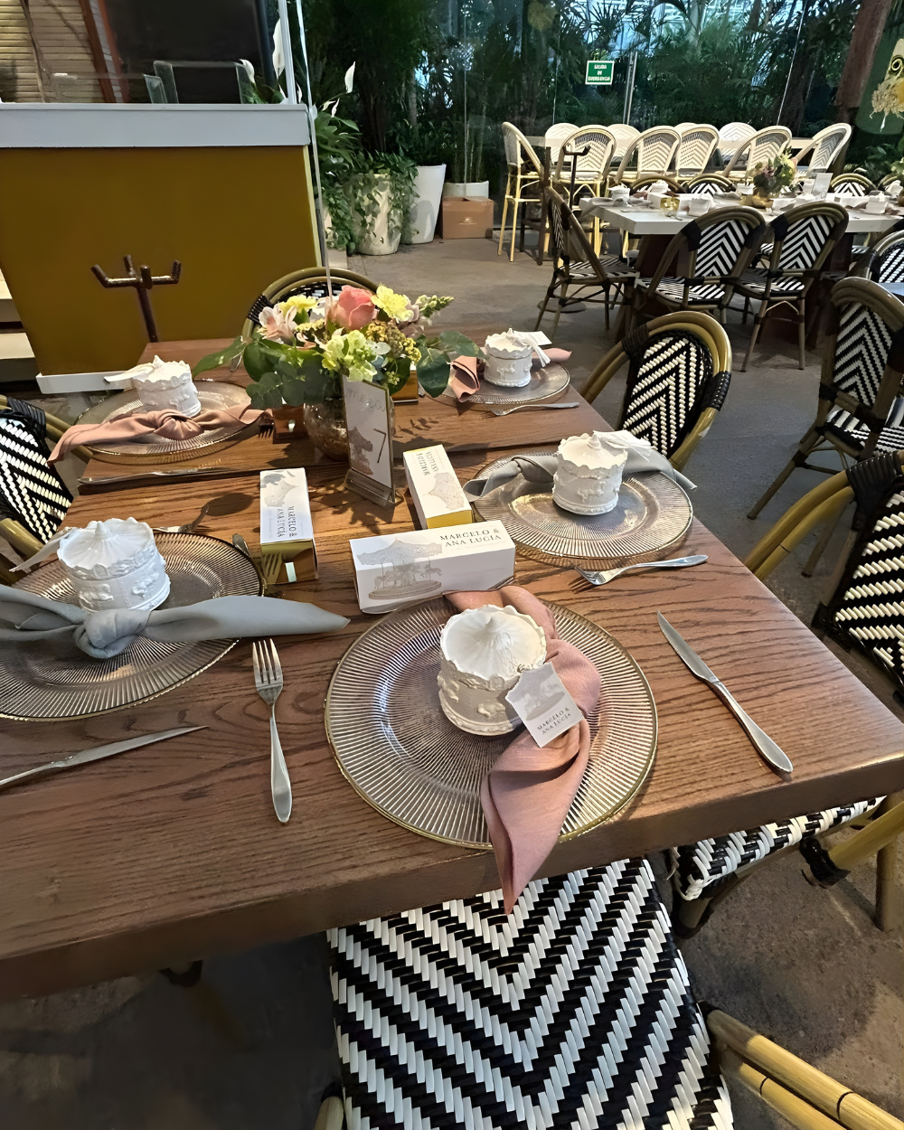 Juego de mesa de comedor con centro de mesa floral, tazas de té, platos y sillas con estampado de espiga en blanco y negro.