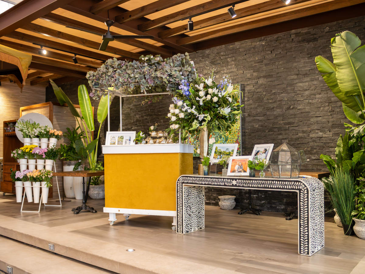 Escenario decorado con arreglos florales, un atril amarillo y una mesa estampada en el interior.