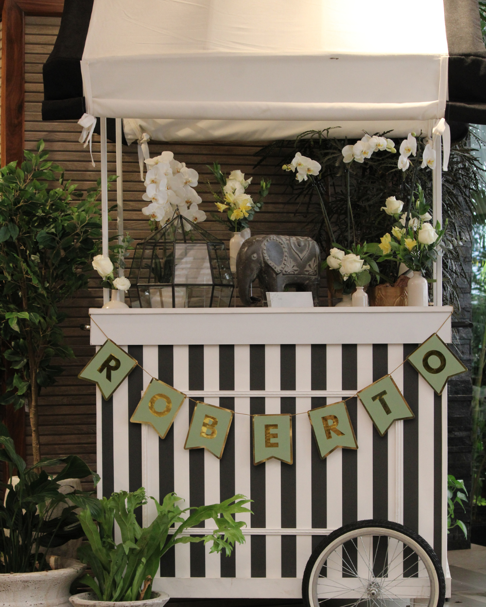 Carrito blanco decorado con frontal a rayas, flores y una pancarta verde con la palabra 