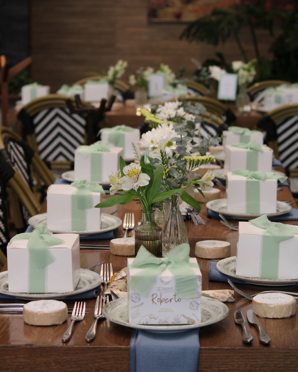 Elegante mesa de banquete con detalles en blanco y verde menta, flores y una cuidada disposición de los cubiertos.