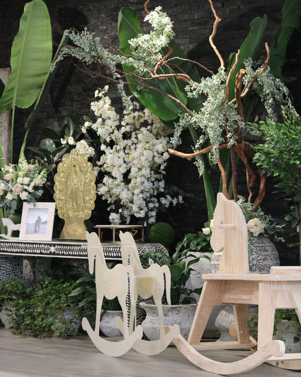 Arreglo floral blanco y mecedoras de madera en un exuberante jardín interior.