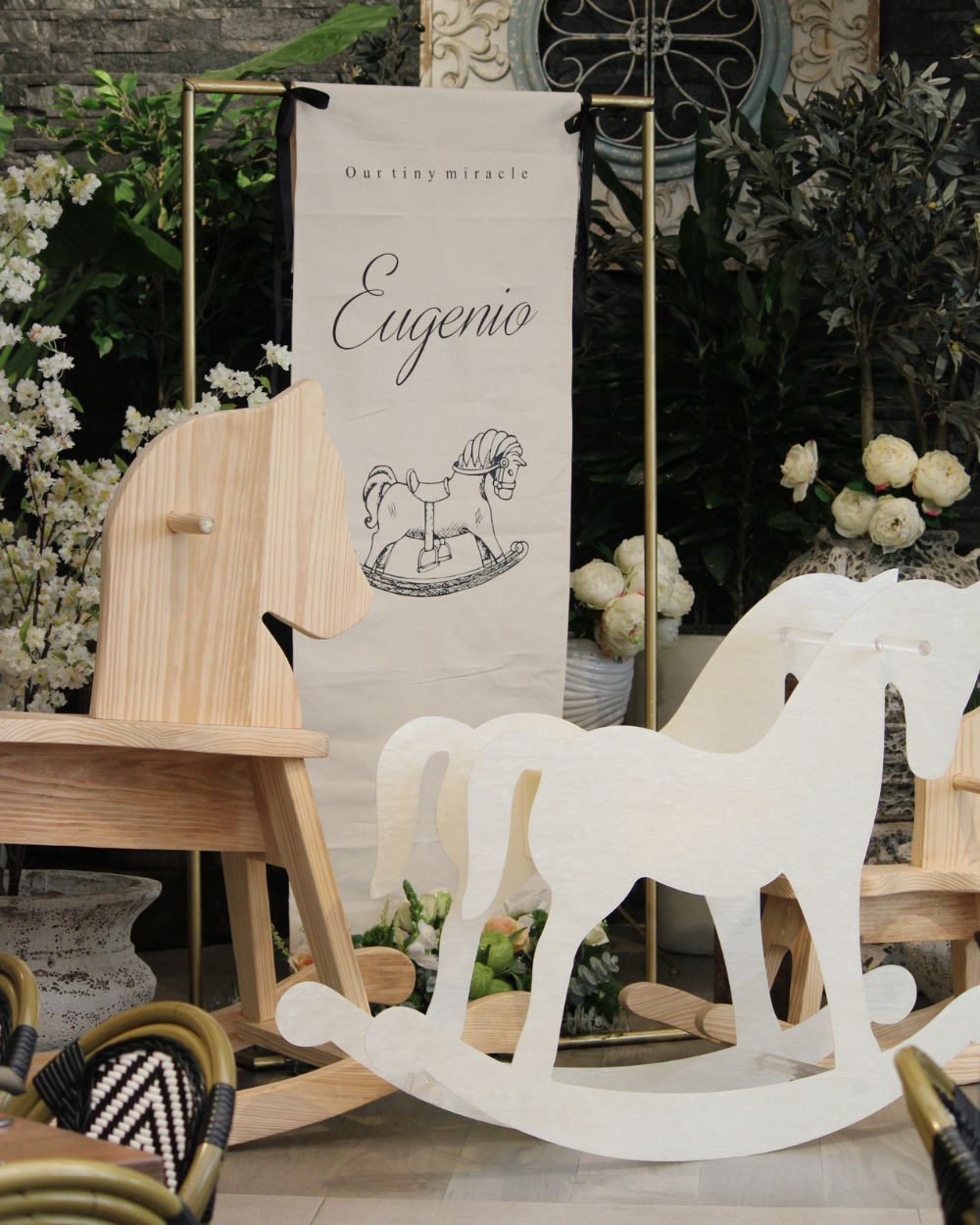 Decoración de fiesta vintage con temática de caballos, con caballito mecedora blanco, pancarta beige y adornos florales.