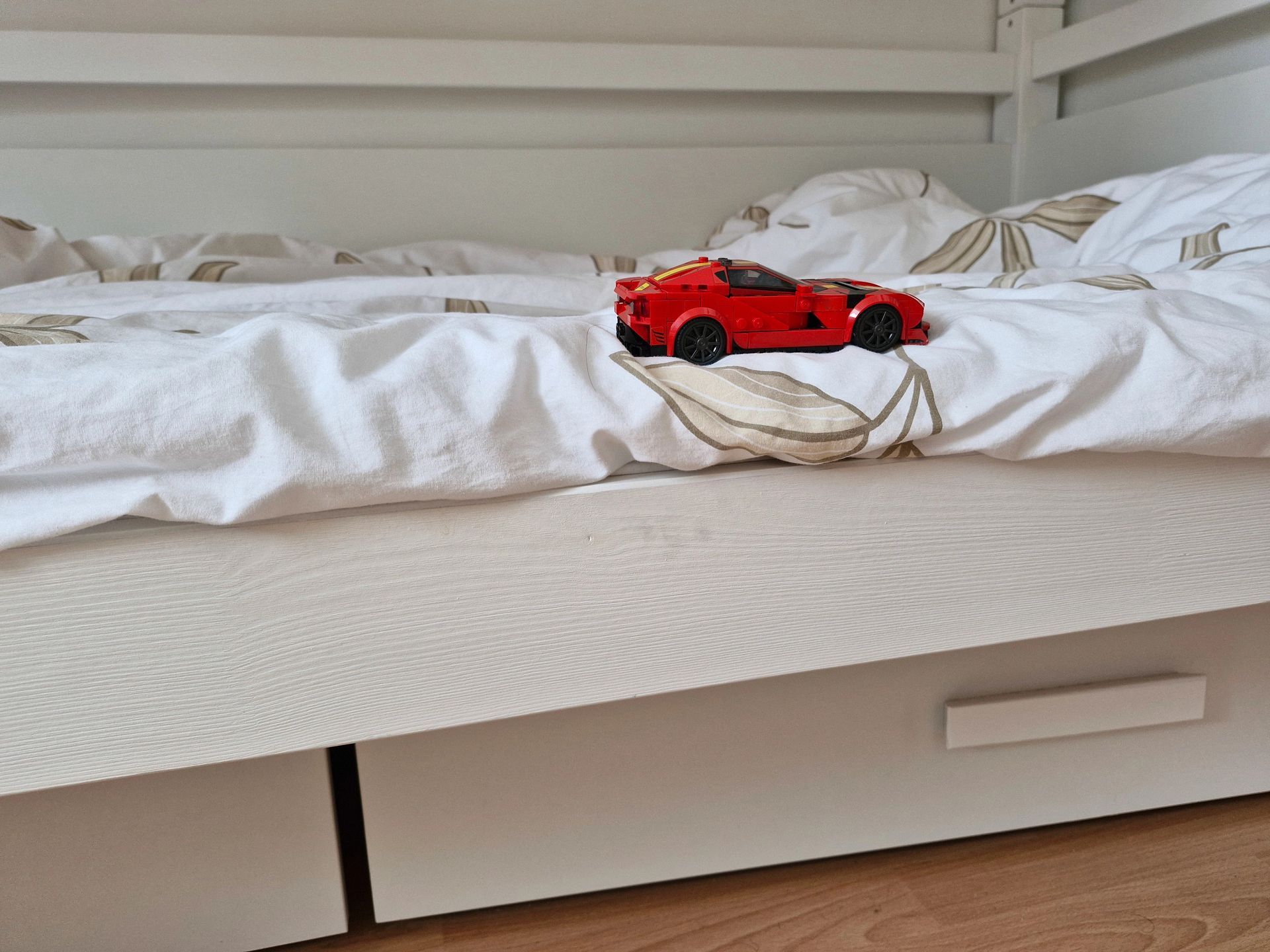 Macchinina sportiva rossa su un letto bianco con lenzuola stropicciate