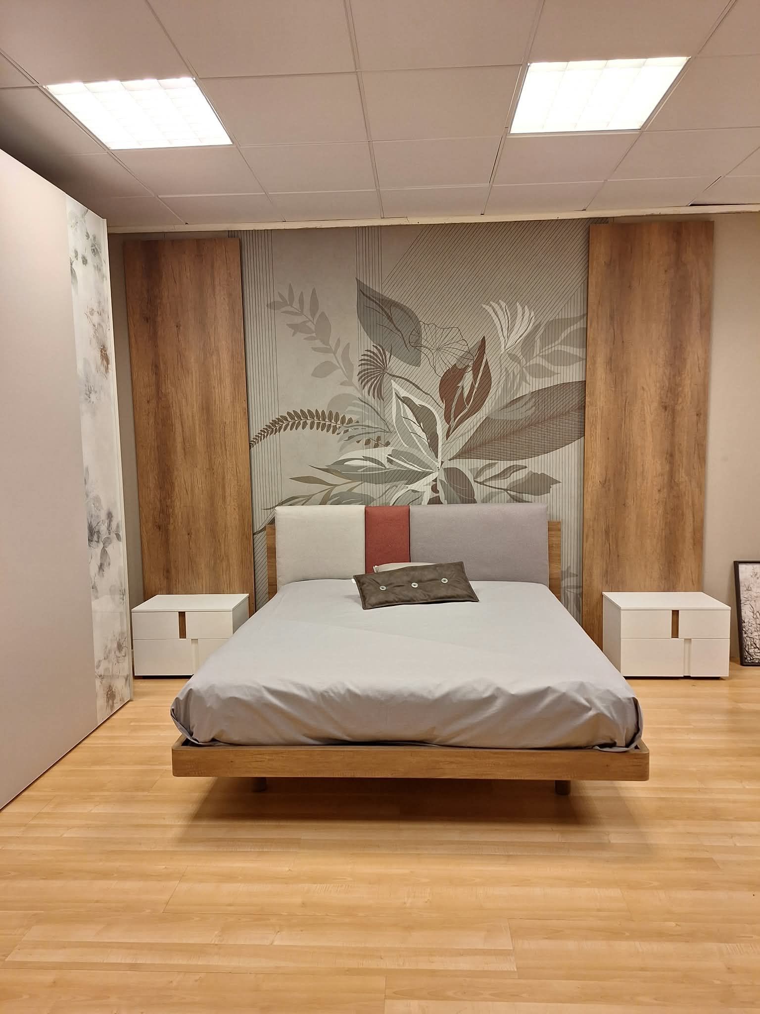 Camera da letto minimalista con un letto in legno, biancheria da letto grigia e pannelli murali decorativi alle sue spalle.