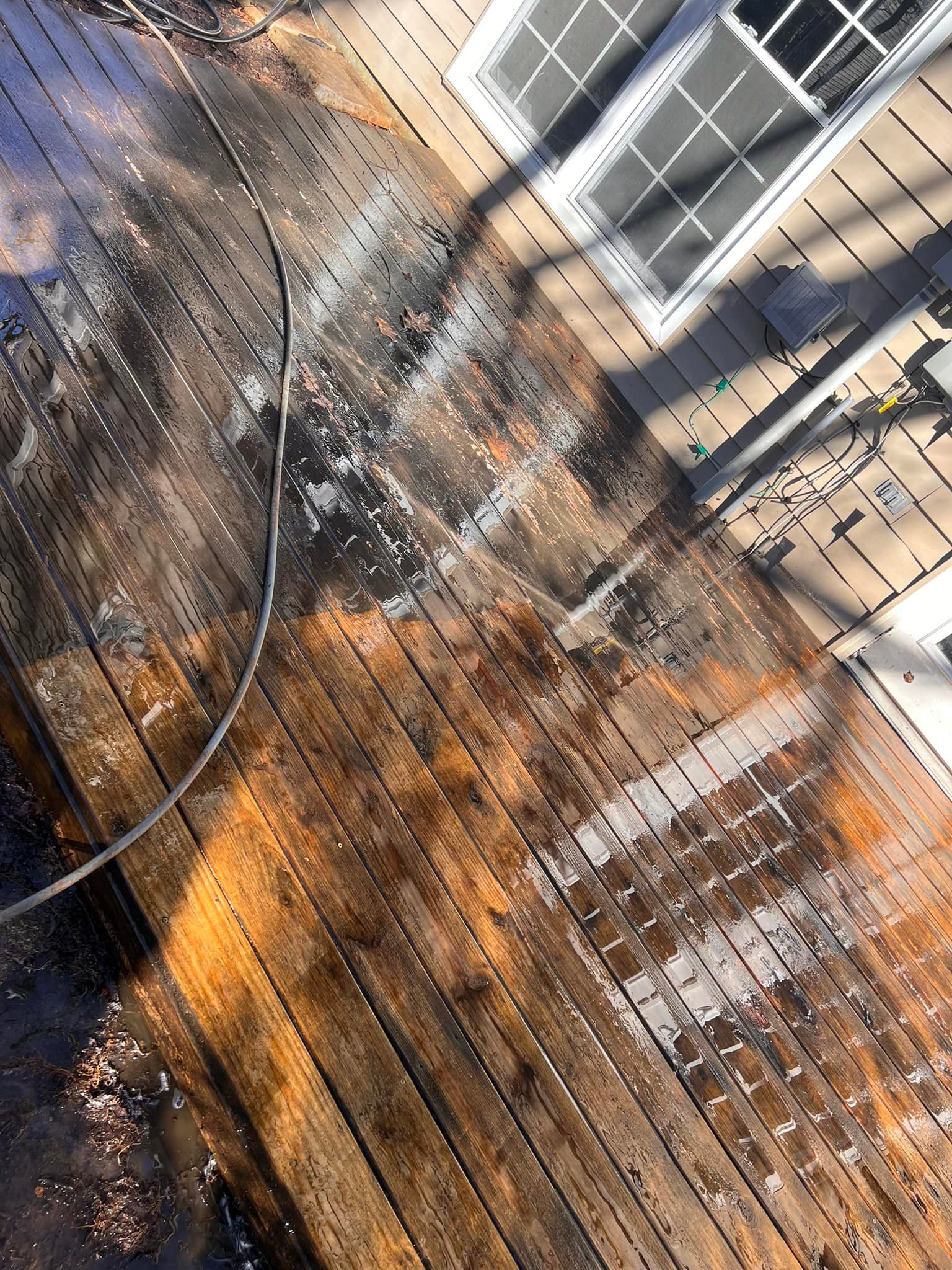 Burnt wooden deck with charred planks, water residue, and a window in the upper right.