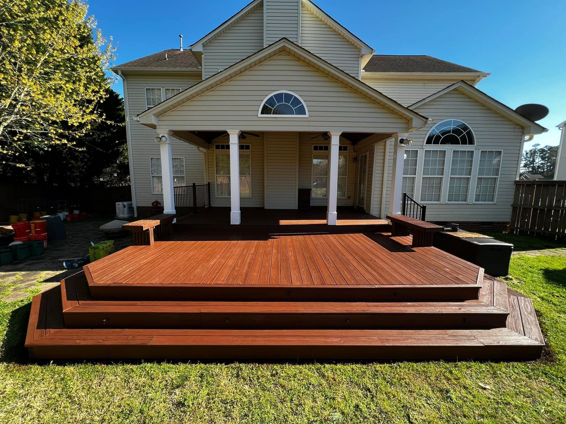Backyard deck with steps, stained reddish-brown wood, leading to a covered porch.