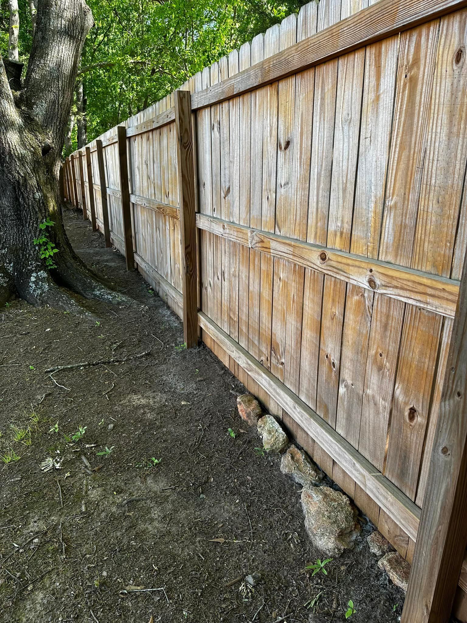 Wooden fence along a dirt path, beside a tree.