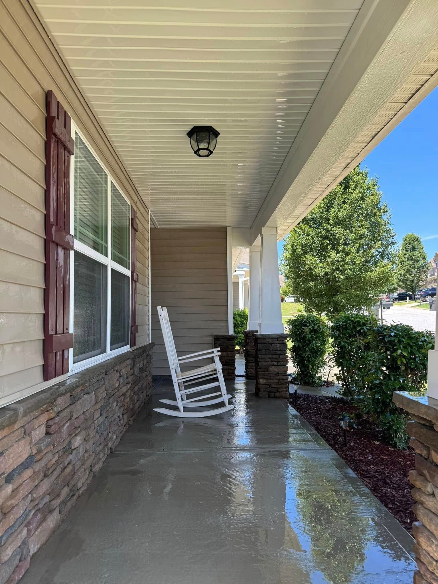 Covered porch with white rocking chair, brown and beige siding, and stone accents.