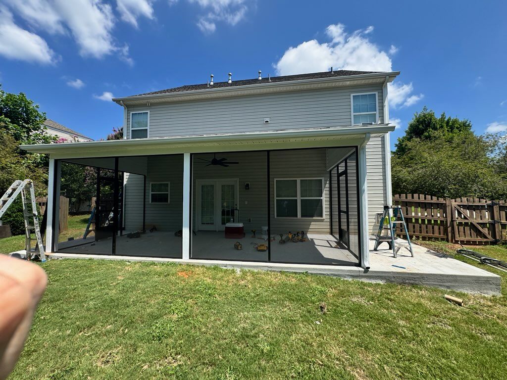 Backyard view of a two-story house with a covered patio and green lawn