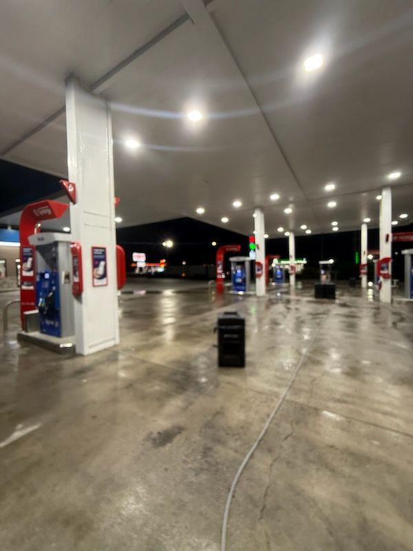 Empty gas station at night with bright lights reflecting on wet pavement
