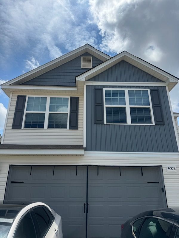 Two-story gray and beige house with a double garage under a cloudy sky