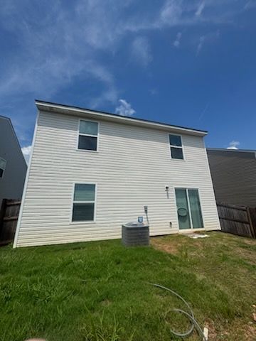 Two-story white house with a green door and lawn under a blue sky