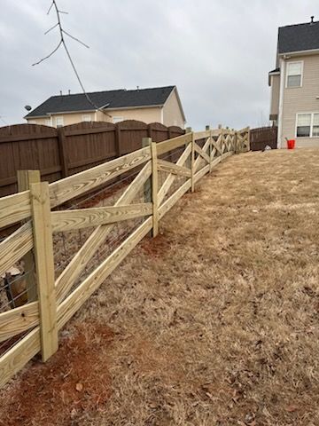 Wooden fence with crisscross design borders a yard with brown grass. Beige house in background.