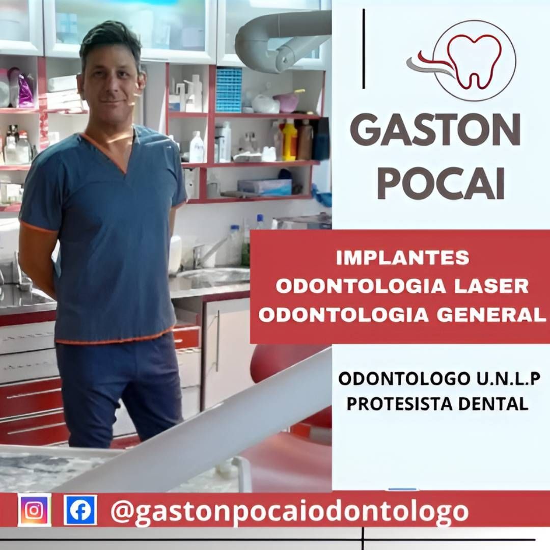 Un dentista con bata azul se encuentra en una clínica junto a un cartel que dice