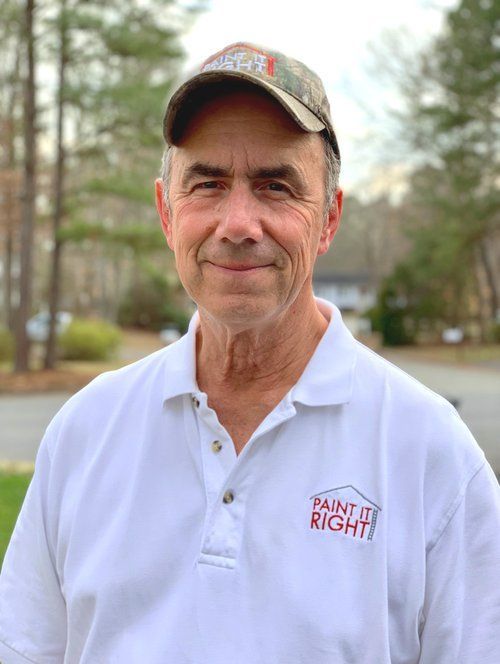 roy parker wearing a white polo shirt and a hat is standing in front of a house