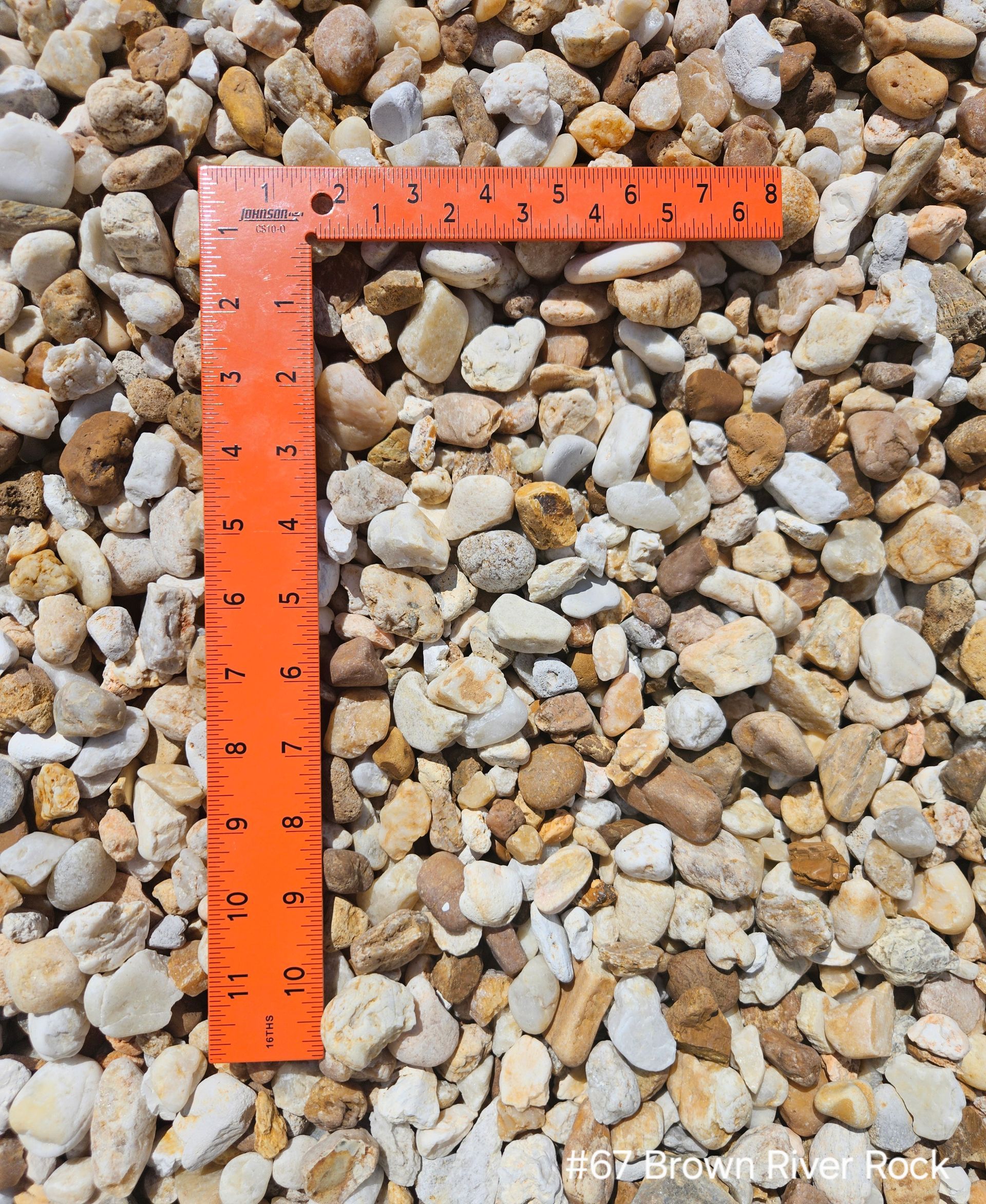 Brown river rocks with orange ruler for scale.
