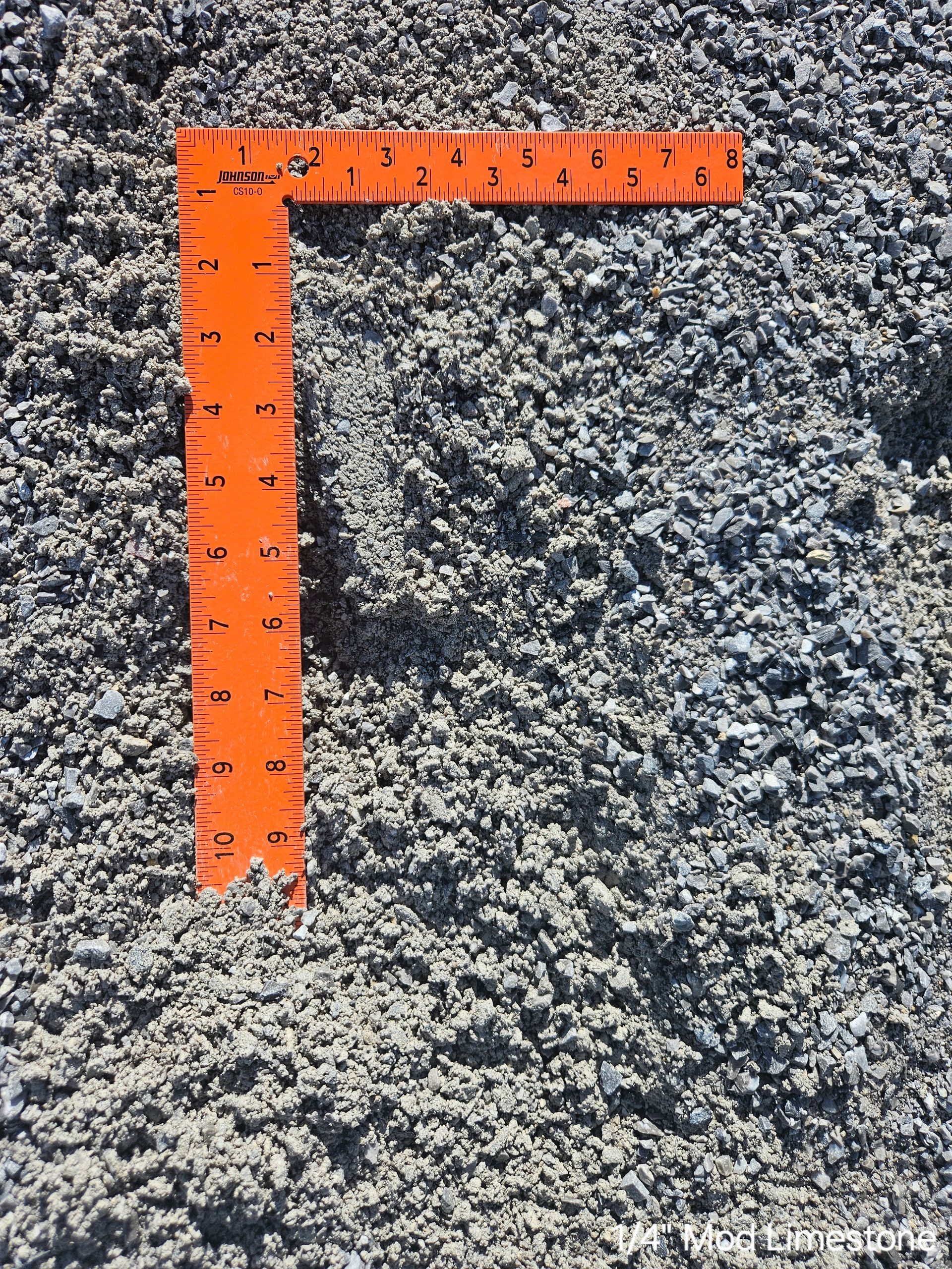 Orange ruler on a pile of gray gravel.