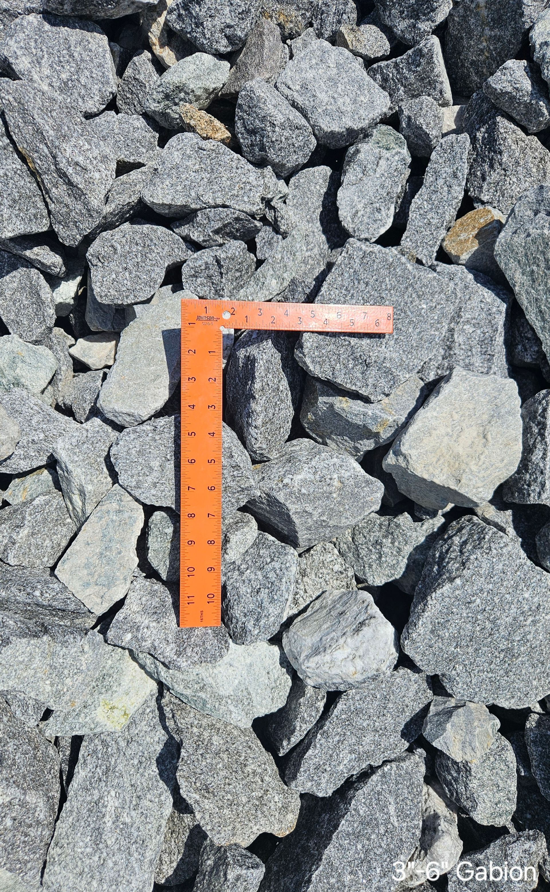 Crushed granite rocks with an orange ruler, showing rock size.