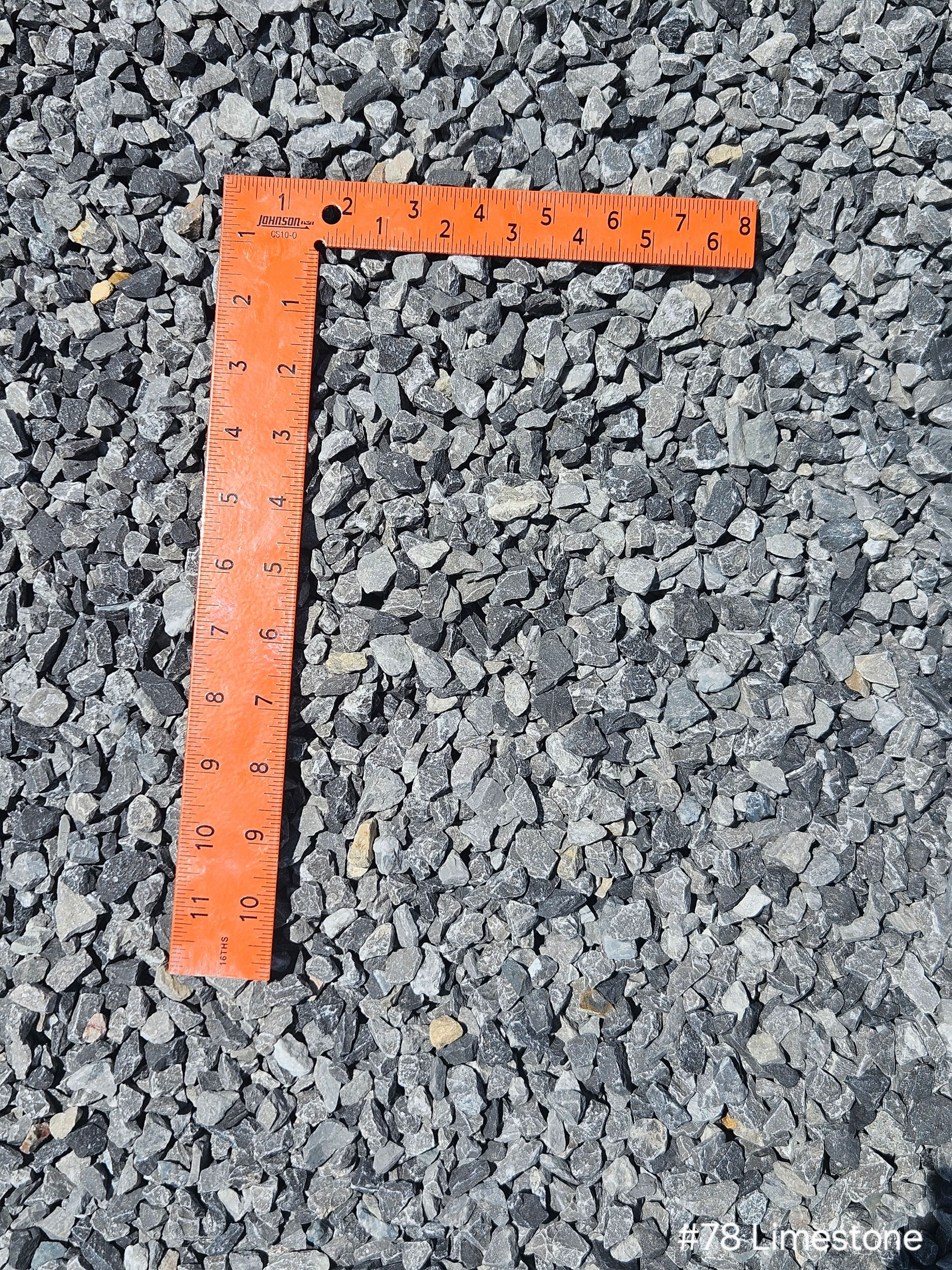 Orange right angle ruler on gray gravel.