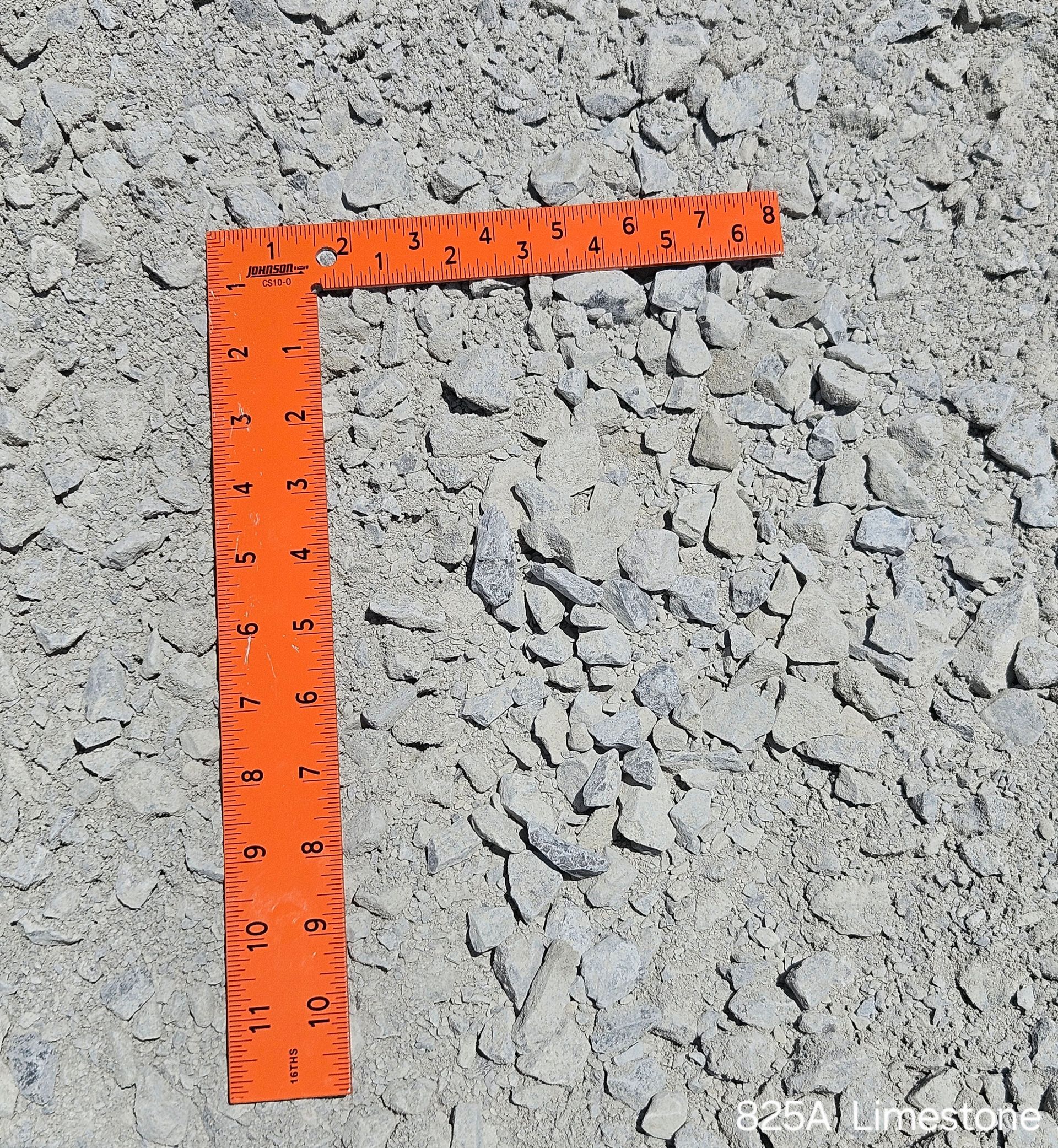 Orange angle ruler on rough, gray, rocky surface.